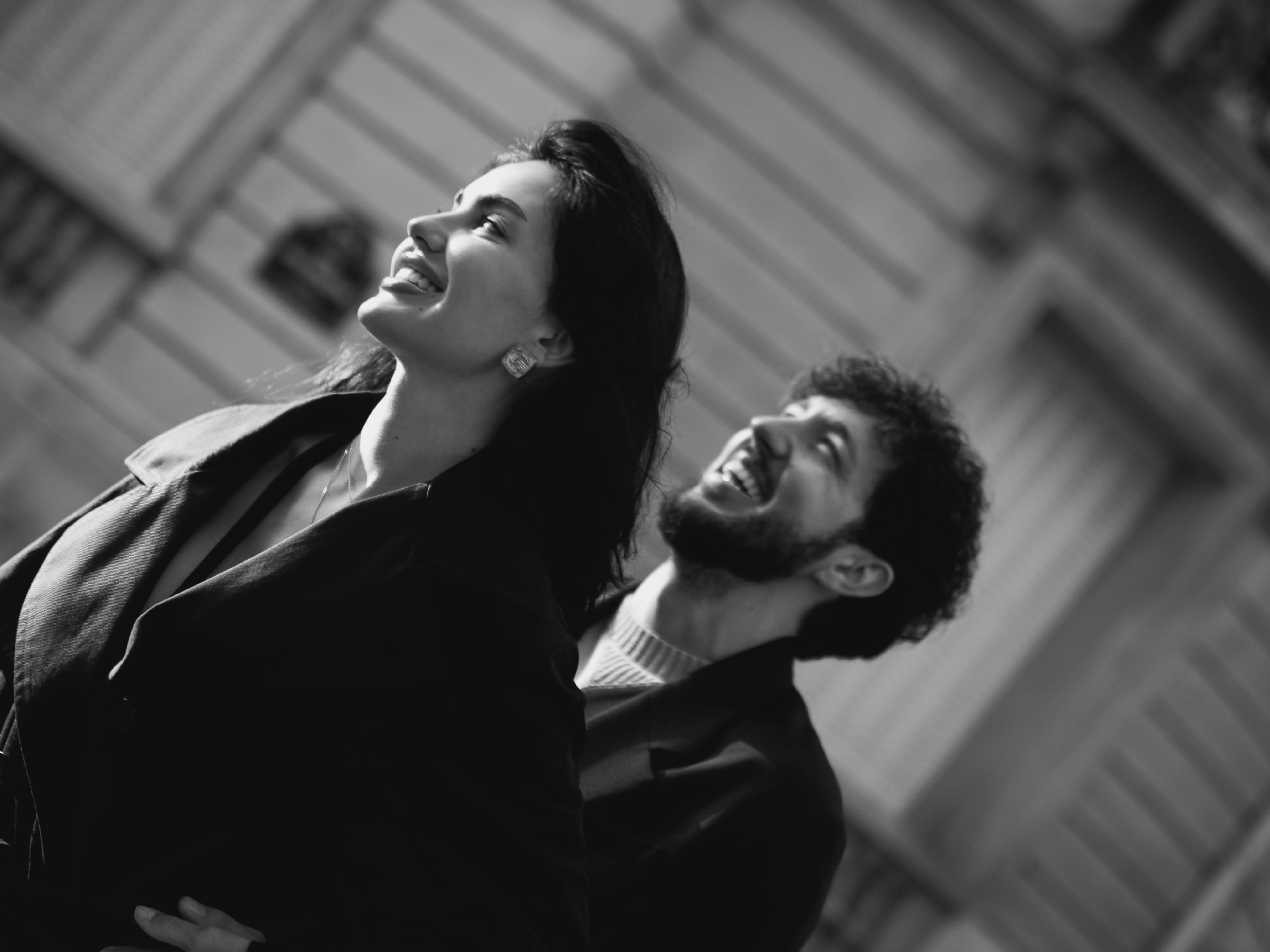 Couple laughing joyfully looking up, architectural background