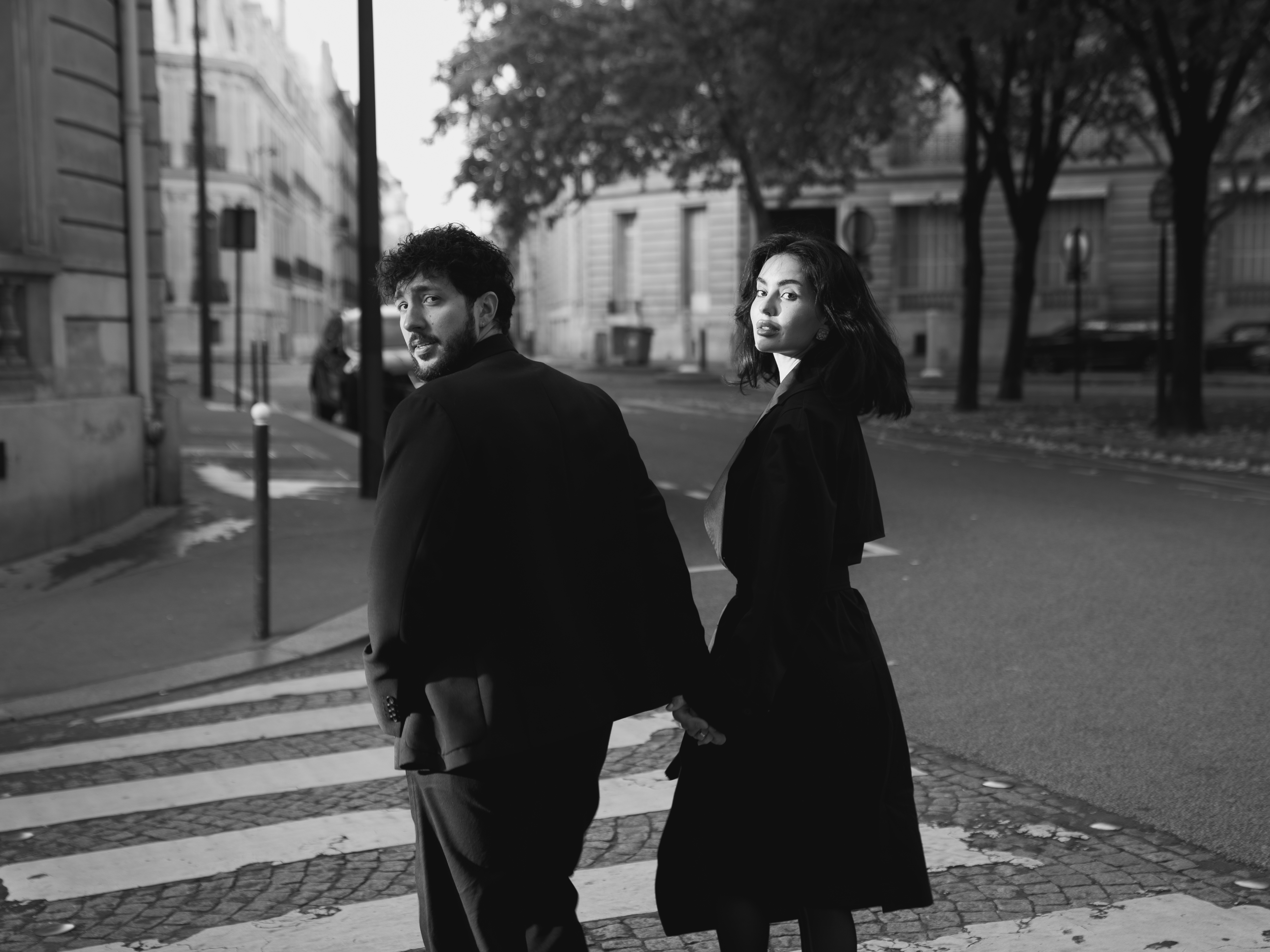Couple standing back-to-back on Parisian street looking over shoulders